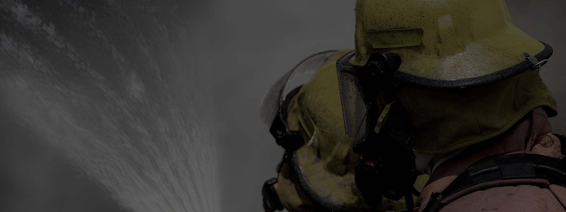 Zwei Feuerwehrmänner bekämpfen einen Brand mit Wasser.